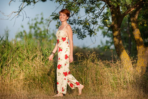 young well dressed redhead woman walks in the countryside