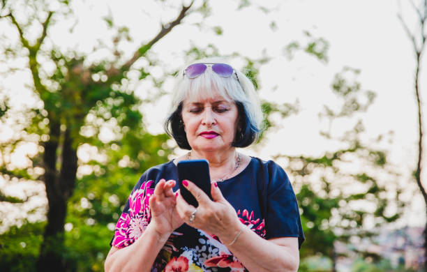 istock Senior Woman using mobile phone outdoor. 1176648425