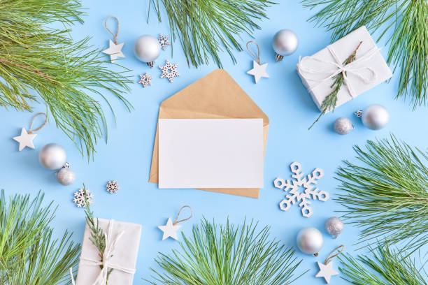 istock Mockup white greeting card and envelope with pine branches and gift box on a blue background 1176651354