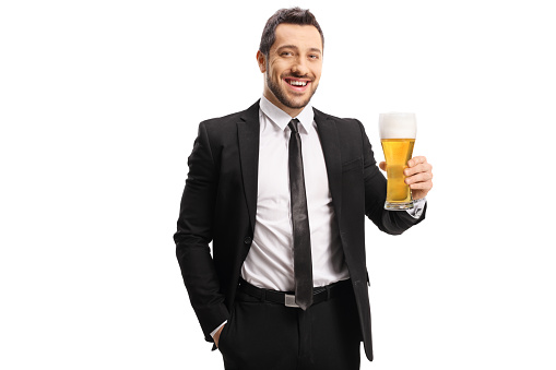 Guy in a suit cheering with a glass of beer and smiling isolated on white background