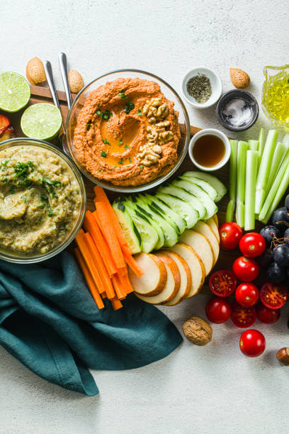 istock veggie serving table with snacks with vegetables, fruits, baba ganoush and dip or spread of roasted red pepper and nuts. healthy vegan food for celebration or friends. shot from above. copy space 1176652303