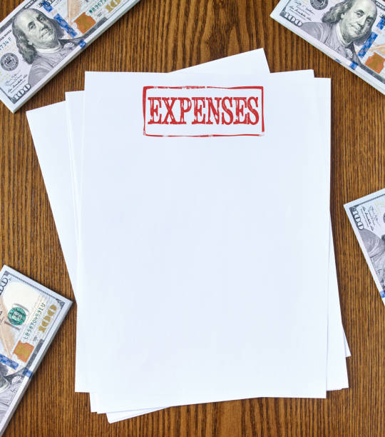 Expenses Looking down on wooden desk with blank paper with “expenses” stamp 100 dollar bills one hundred dollar stamp stock pictures, royalty-free photos & images
