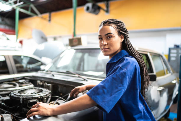 Portrait of woman repairing a car in auto repair shop Portrait of woman repairing a car in auto repair shop stereotypical stock pictures, royalty-free photos & images