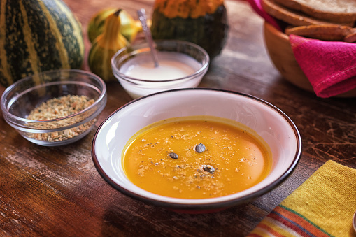 Hot pumpkin soup in plate on rustic table, close-up