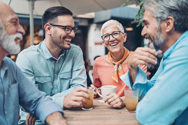 Group of smiling people talking in cafe Group of people at different ages drinking and talking in cafe group of people wearing eyeglasses stock pictures, royalty-free photos & images