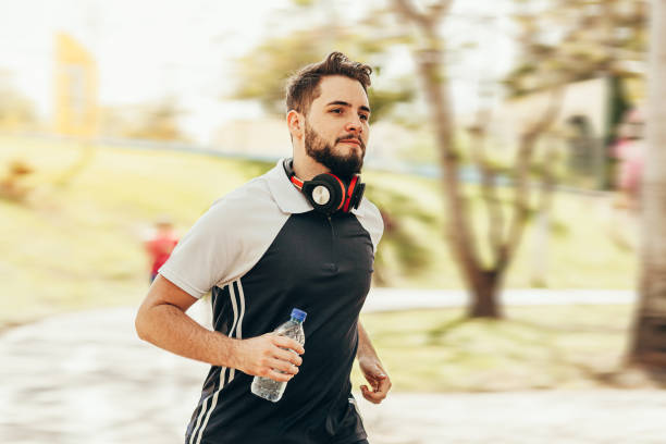 istock Runner athlete running in park holding water bottle 1176665804