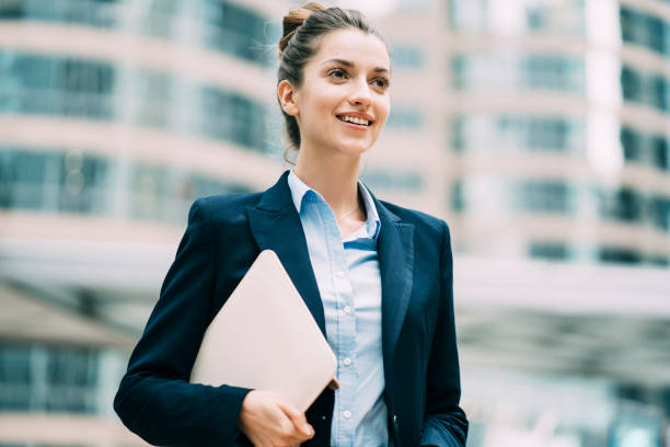 istock Smiling woman holding documents and walking on street 1176667272