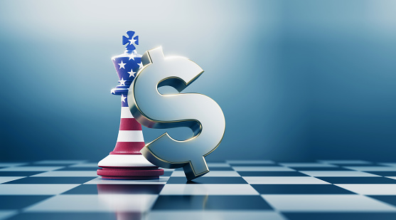 Single king chess piece and metallic American dollar sign are standing on black and white chessboard. King chess piece is textured with American flag. Horizontal composition with selective focus and copy space. Great use for American dollar concepts.