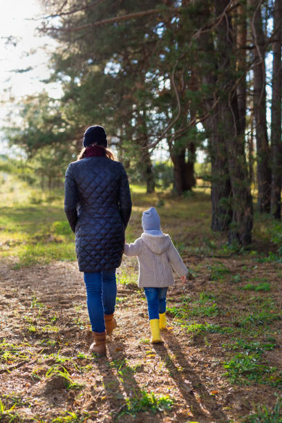 istock Mother holding her kid's hand while walking together in the forest 1176673734