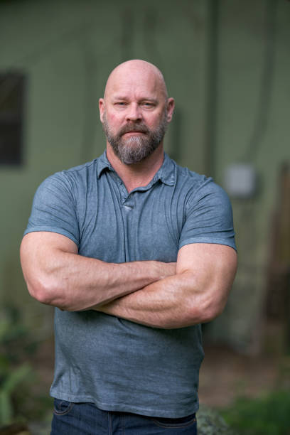 istock Macho tough guy posing with arms crossed. Man is bald with a full beard 1176676100
