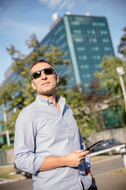 istock Handsome guy with his smartphone in bright sunlight looking into the sun 1176676367