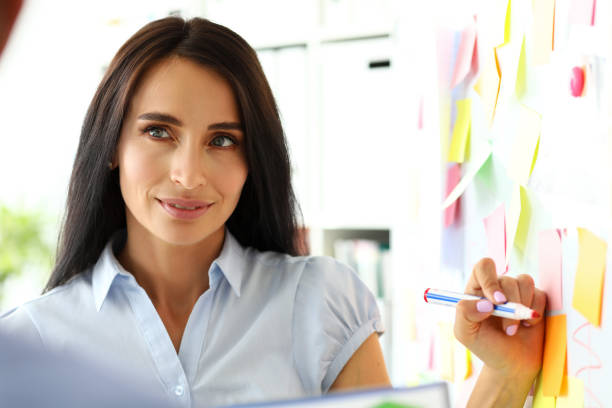 istock Beautiful female clerk drawing something on whiteboard during business conversation 1176676611