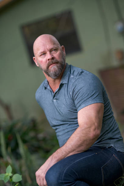 istock Handsome mature man sitting with arm on leg. Man is bald with graying beard 1176676927