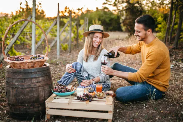 Photo of Young couple tasting wine at vineyard
