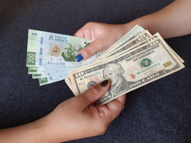 women hands exchanging mexican banknotes and american dollar money - taxa de câmbio imagens e fotografias de stock