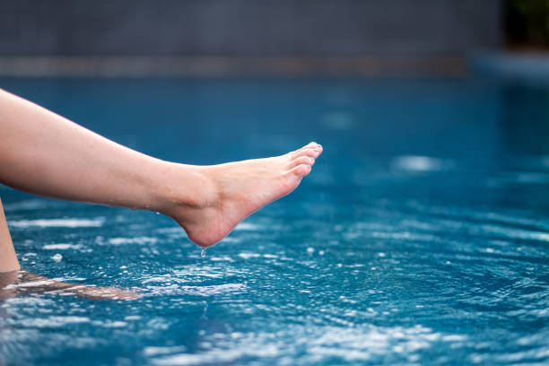istock legs and barefoot kicking and soaking water in the pool 1176692041