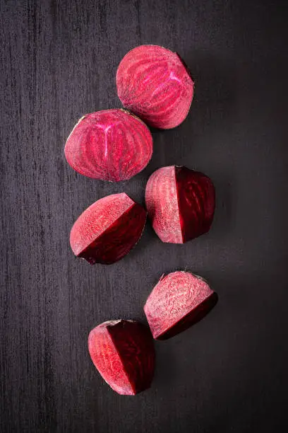 Tasty raw beetroot. Sliced beetroot on black kitchen table. Top view.