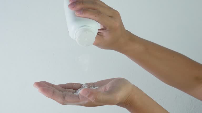 Close-up hand of woman pouring talcum powder onto the palm, isolated on white background.