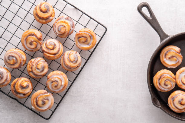 Homemade baked cinnamon rolls baked in an iron skillet cooling on cooling rack with icing stock photo