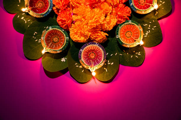glücklich dussehra. clay diya lampen während dussehra mit gelben blumen, grünem blatt und reis auf rosa pastell hintergrund beleuchtet. dussehra indian festival konzept. - dashahara stock-fotos und bilder