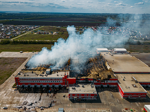 Burning industrial distribution warehouse, aerial drone view.