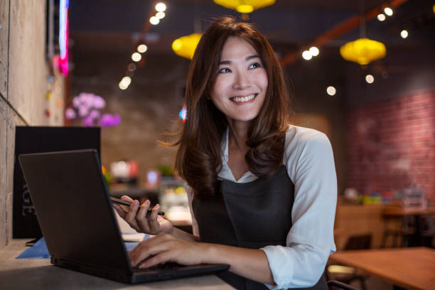 彼女のビジネスプランのためのいくつかのアイデアを持っている若いアジアのカフェの所有者 - small business restaurant asian ethnicity asia ストックフォトと画像