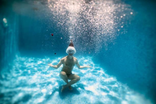 istock Man playing with baubles in pool on summer Christmas 1176704177