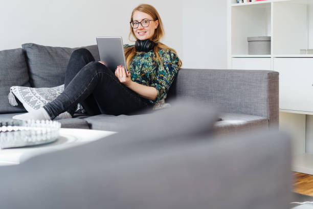 istock Young woman relaxing on a couch with a tablet 1176707362