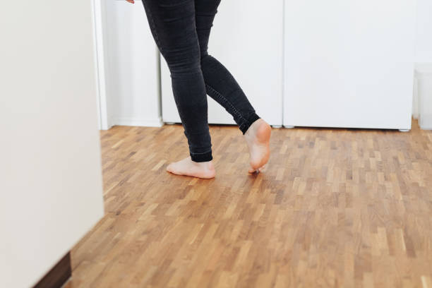 Barefoot young woman walking across a wooden floor stock photo
