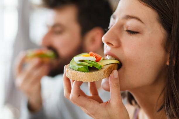 nahaufnahme von jungen frau beißen in ein sandwich - lebensfreude essen stock-fotos und bilder