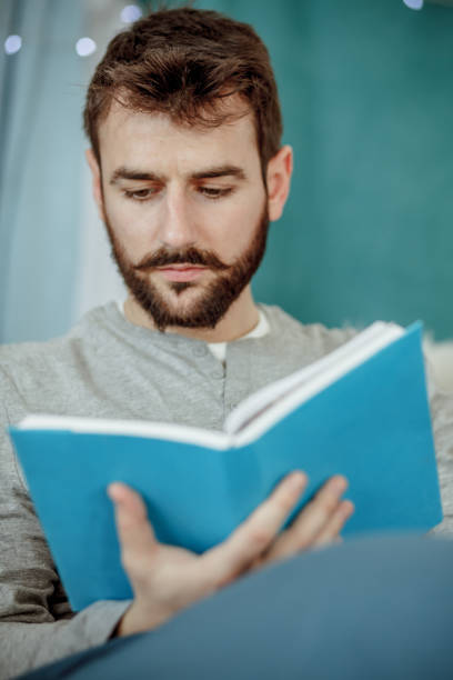 istock Young man reading a book before going to sleep 1176710186