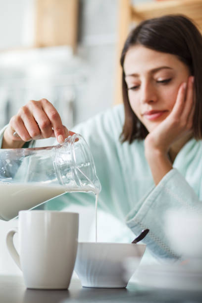 istock Young woman adding milk in her cereal 1176710944
