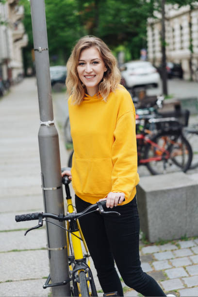 Smiling young woman standing beside a bicycle