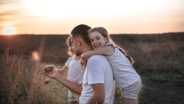 istock Dad and his daughters in the field at sunset . 1176712727