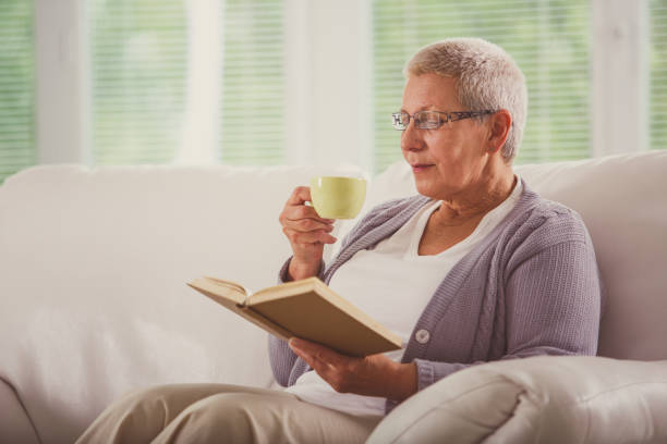 istock Happy senior woman enjoying a cup of coffee while reading a book 1176713938