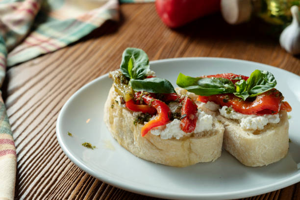 bruschetta com pimenta de sino, manjericão, molho do pesto e mozzarella em uma placa branca em um fundo de madeira. restaurante italiano. foto do alimento da vista superior - antipasto roasted pepper bell pepper pepper - fotografias e filmes do acervo