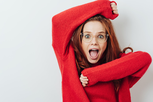 Exuberant young woman yelling in delight with her arms raised, wide eyes and open mouth isolated on white with copy space