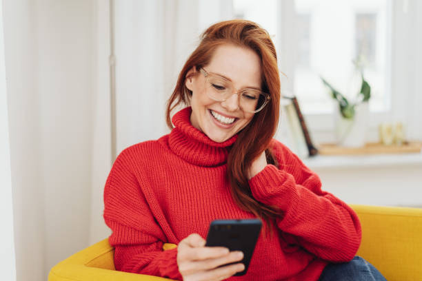 smiling girl looking at smartphone - red yellow imagens e fotografias de stock
