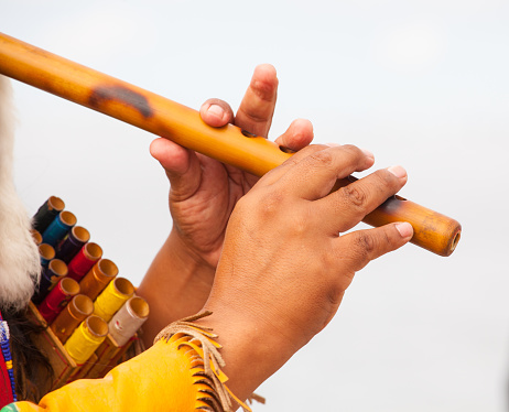 Close up of Peruvian man in native costume playing flute