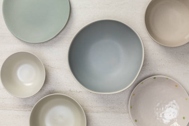 istock Group of empty blank ceramic round bowls and plates on white stone blackground, Top view of traditional handcrafted kitchenware concept 1176719491