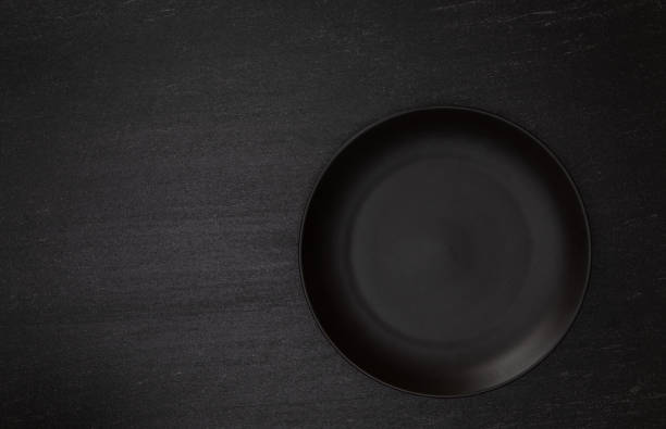 istock Empty blank black ceramic round plate or dish on black stone blackground with copy space, Top view of traditional handcrafted kitchenware concept 1176719498