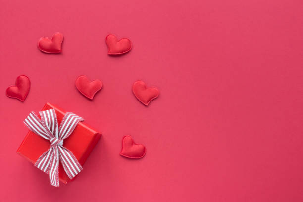 istock Red gift box with ribbon and hearts on red background. Top view card 1176721133