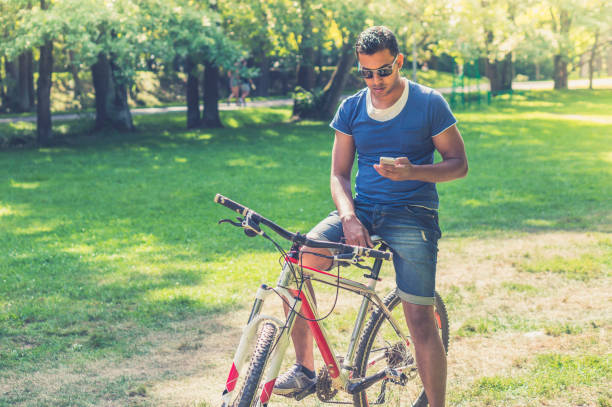 istock Young Indian man on bicycle watching smartphone 1176722331