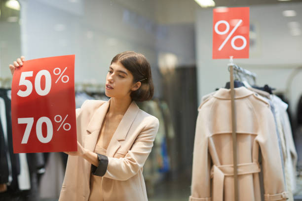 woman hanging sale signs in store - clothing store clothing sale fashion imagens e fotografias de stock