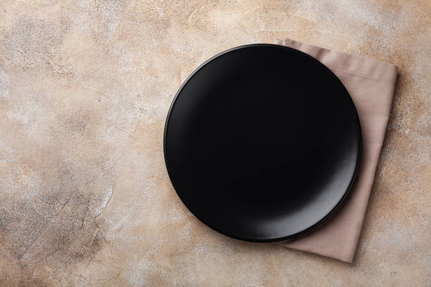 istock Black plate with napkin on stone table top view. Empty space for menu or recipe. 1176723731