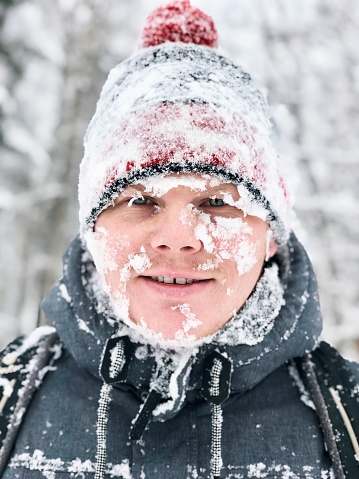 Close up portrait of man with frozen snowy face and hat