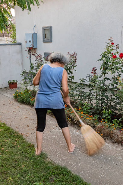 istock Senior Woman is Sweeping the Backyard with Broom 1176725543