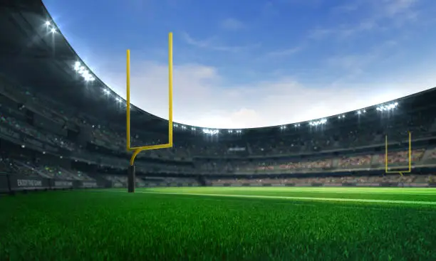 Photo of American football league stadium with yellow goalposts and fans, daytime field view