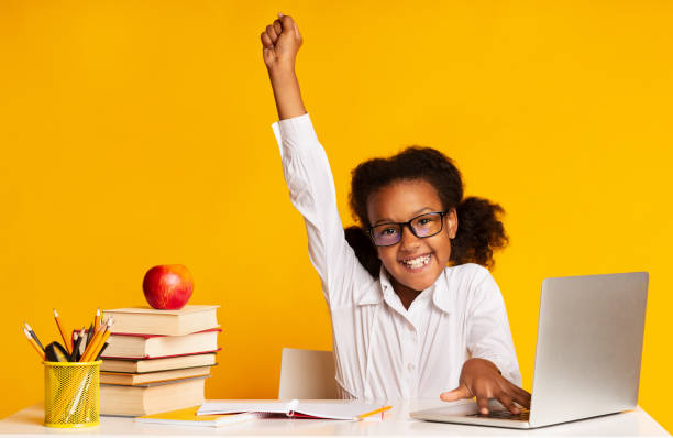 Elementary Student Girl Raising Hand Sitting At Laptop, Studio Shot