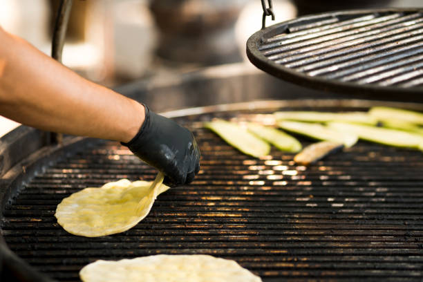 Man frying round cakes on big grill outdoor